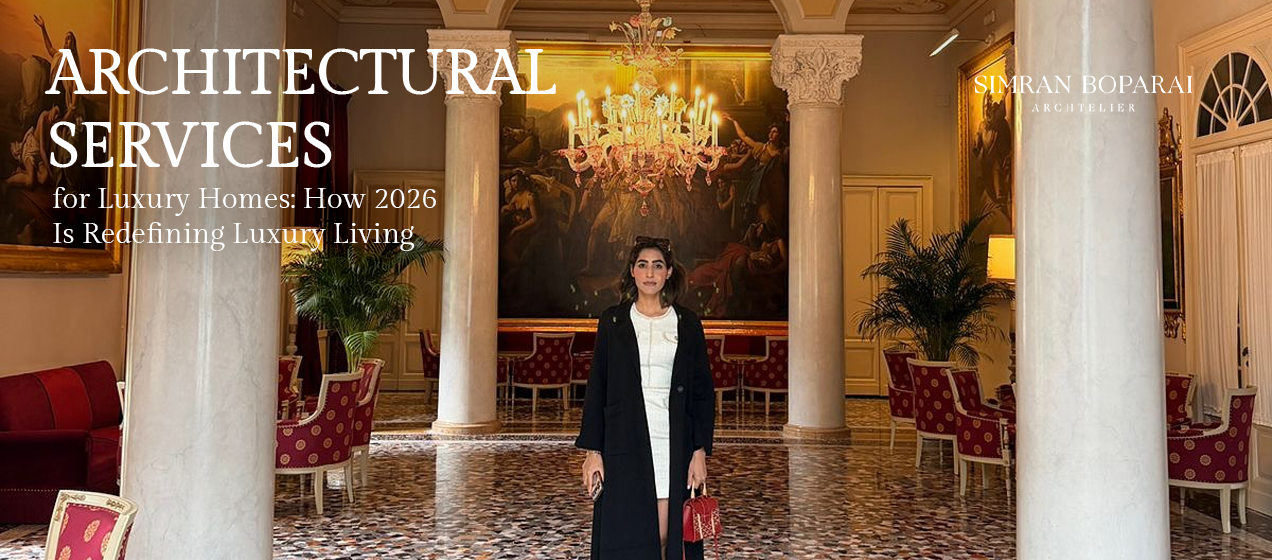 "Luxury architectural interior featuring grand classical columns, an elegant crystal chandelier, ornate artwork, and a designer standing in the center of the space, alongside the text 'Architectural Services for Luxury Homes: How 2026 Is Redefining Luxury Living' with Simran Boparai Archtelier branding."